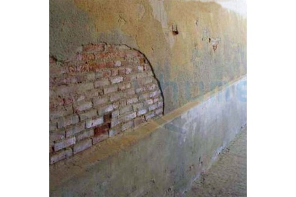 Pared desconchada con humedad y manchas blancas.