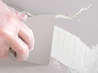 Aplicación de la masilla con espátula sobre una pared agrietada